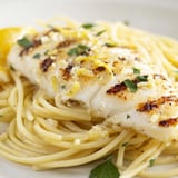 A close-up of Lemon Bass Pasta with flaky fish, glistening sauce, and a sprinkle of grated Parmesan cheese.