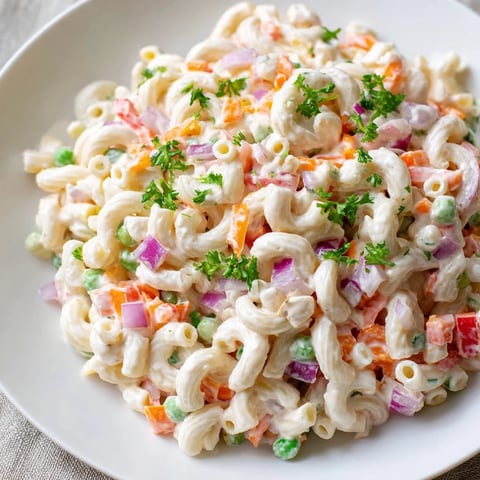 Creamy macaroni salad, a classic side, features chilled pasta with colorful diced vegetables.