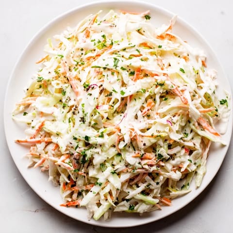 Vibrant image of homemade Coleslaw with Apple, tossed in a creamy dressing, ideal for summer gatherings.