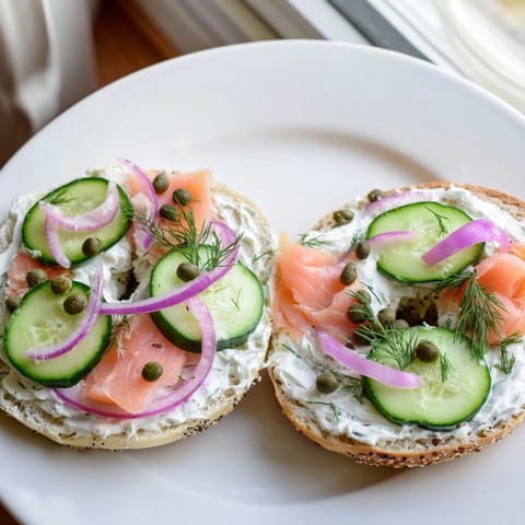 Toasted bagel with cream cheese, ready to enjoy with fresh sliced cucumber and tomatoes.