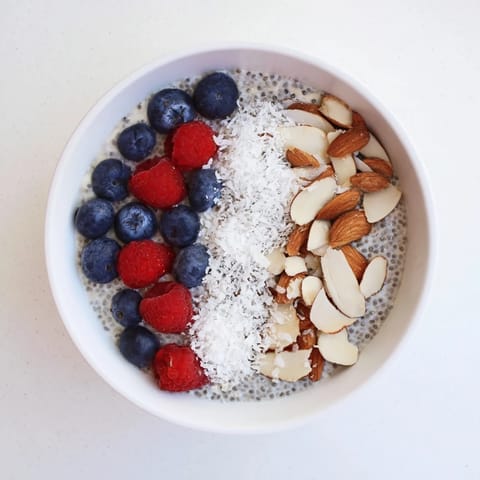 Fresh Poppy Seed Chia Pudding topped with blueberries, toasted almonds, and coconut in a glass jar.
