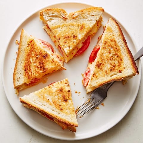 Spicy Pepper Jack & Tomato Grilled Cheese served with a ripe tomato slice and melted cheese on a plate.