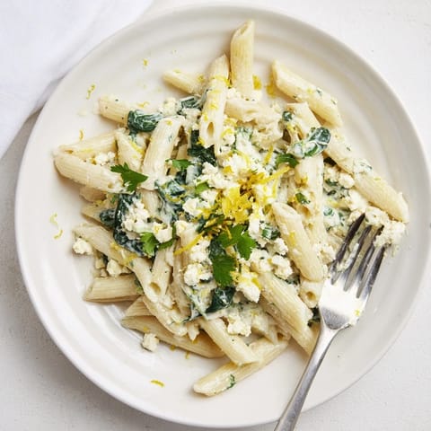 Savory Creamy Feta Spinach Pasta plated, garnished with lemon zest and fresh basil.  