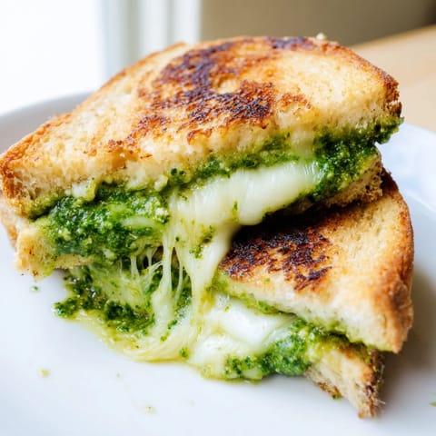 Freshly grilled Spring Pea Pesto Grilled Cheese with melty mozzarella, served warm with arugula on a rustic table.