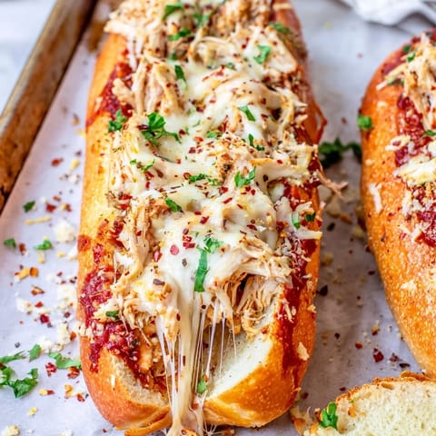 Freshly baked Italian-American Chicken Parm Stuffed Garlic Bread with melted cheese and savory herbs on a rustic board.