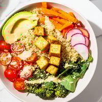 A colorful Buddha bowl overflowing with quinoa, tofu, and vibrant vegetables, ready to eat.
