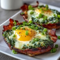 Green eggs and ham breakfast cups with spinach and melted cheese in a muffin tin.